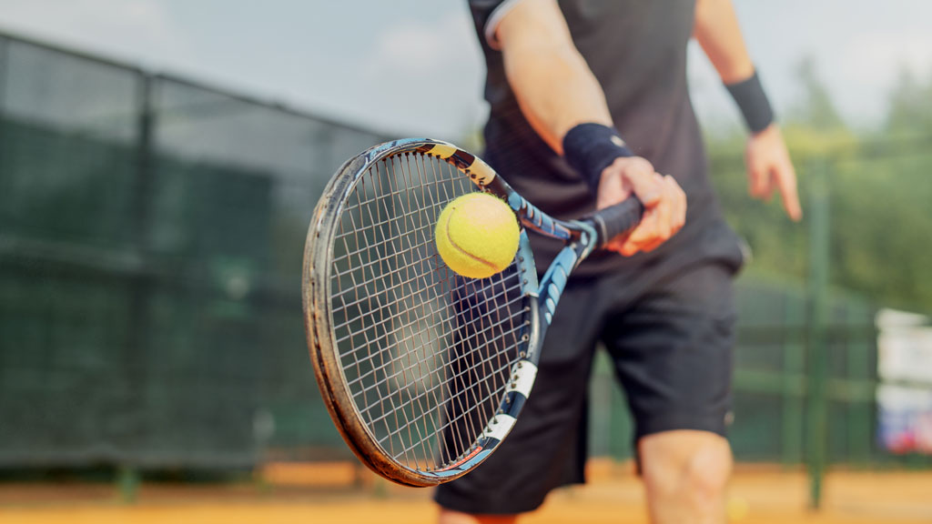 Adolescent concentré en position de préparation de service pendant un entraînement de stage tennis intensif